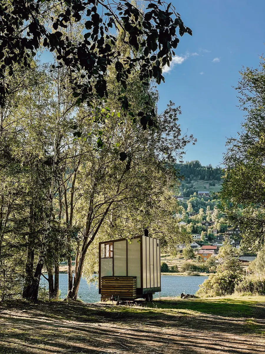 The sauna parked under the birches on the lakeshore at Ål