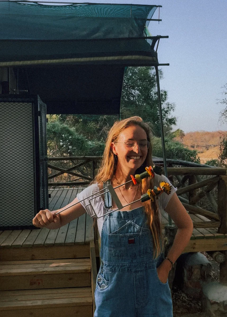 Evelyne holding up the Brändi Grillspiess, loaded with vegetables, in the late afternoon sun