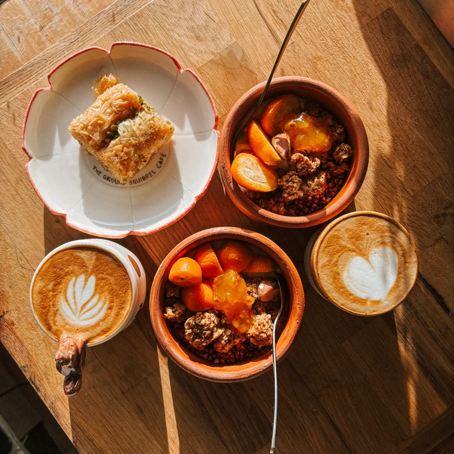 Baklava, granola bowls and two coffees on a sunlit wooden table