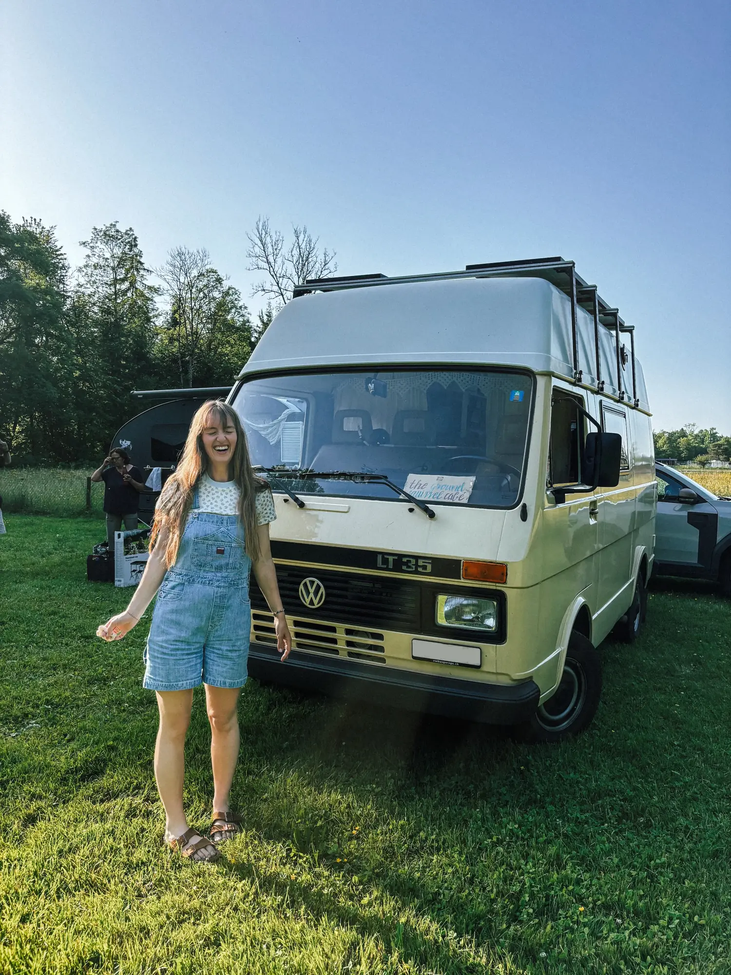 evelyne beaming in front of humbär on a summer meadow