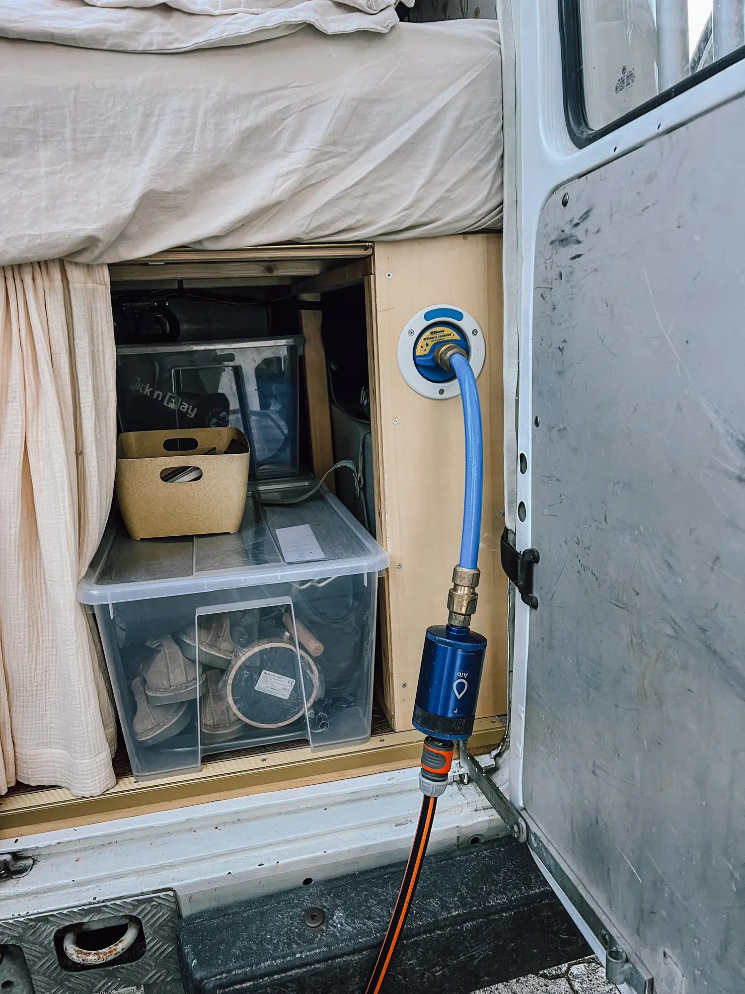 a blue alb filter housing on the hose at the van's water inlet
