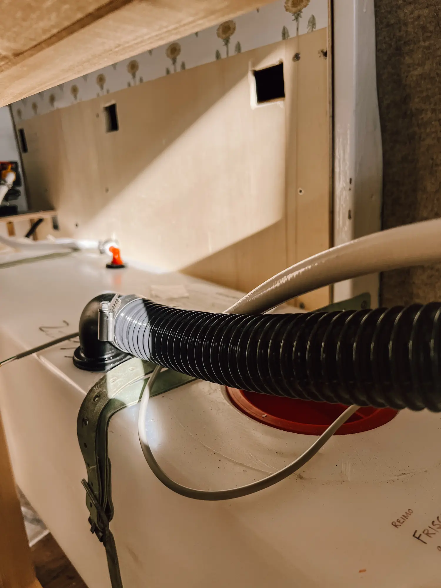 a spiral hose running into the fresh water tank, its red lid beside it