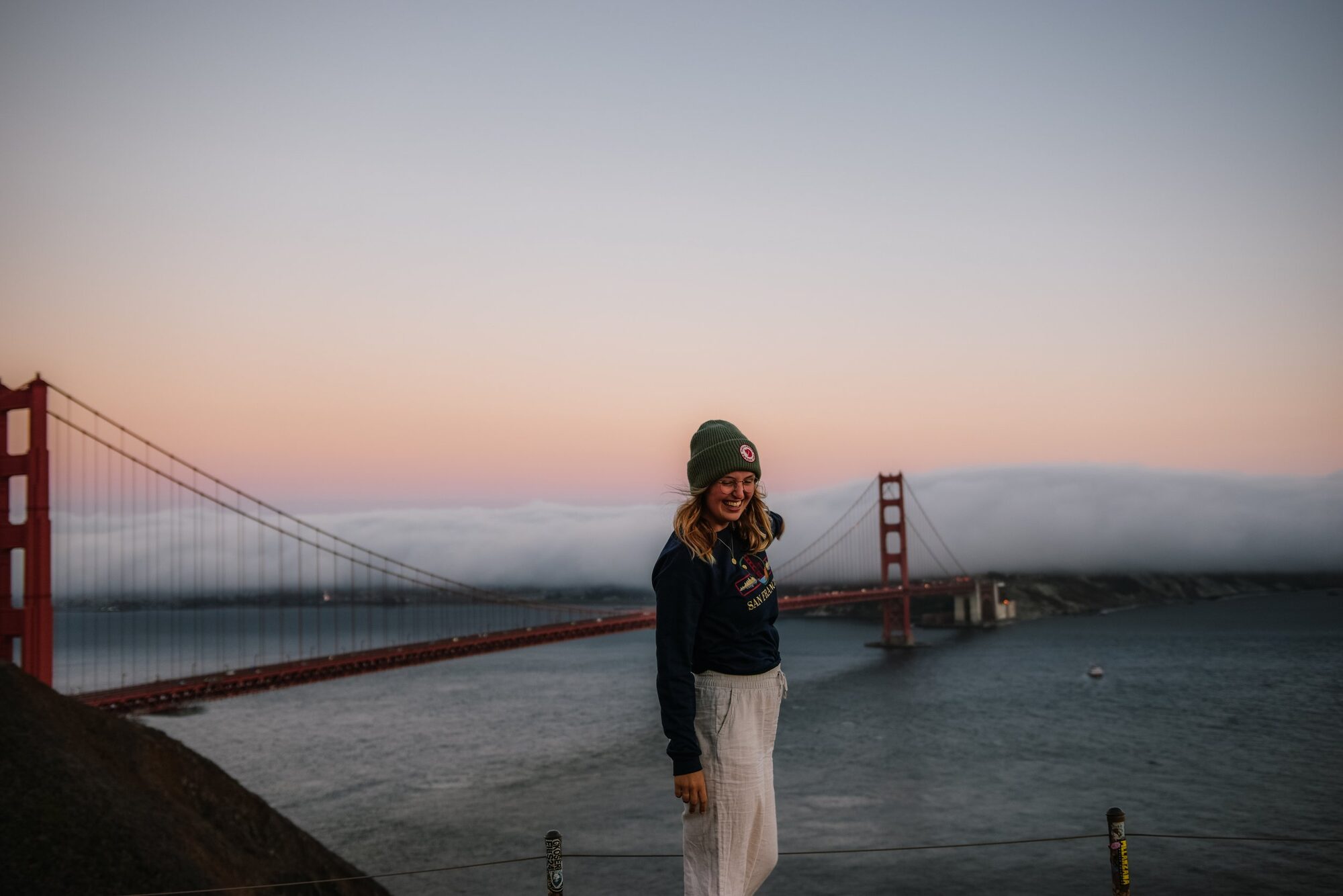 what a poetic moment! golden gate bridge in the pink sky above fluffy clouds of san francisco