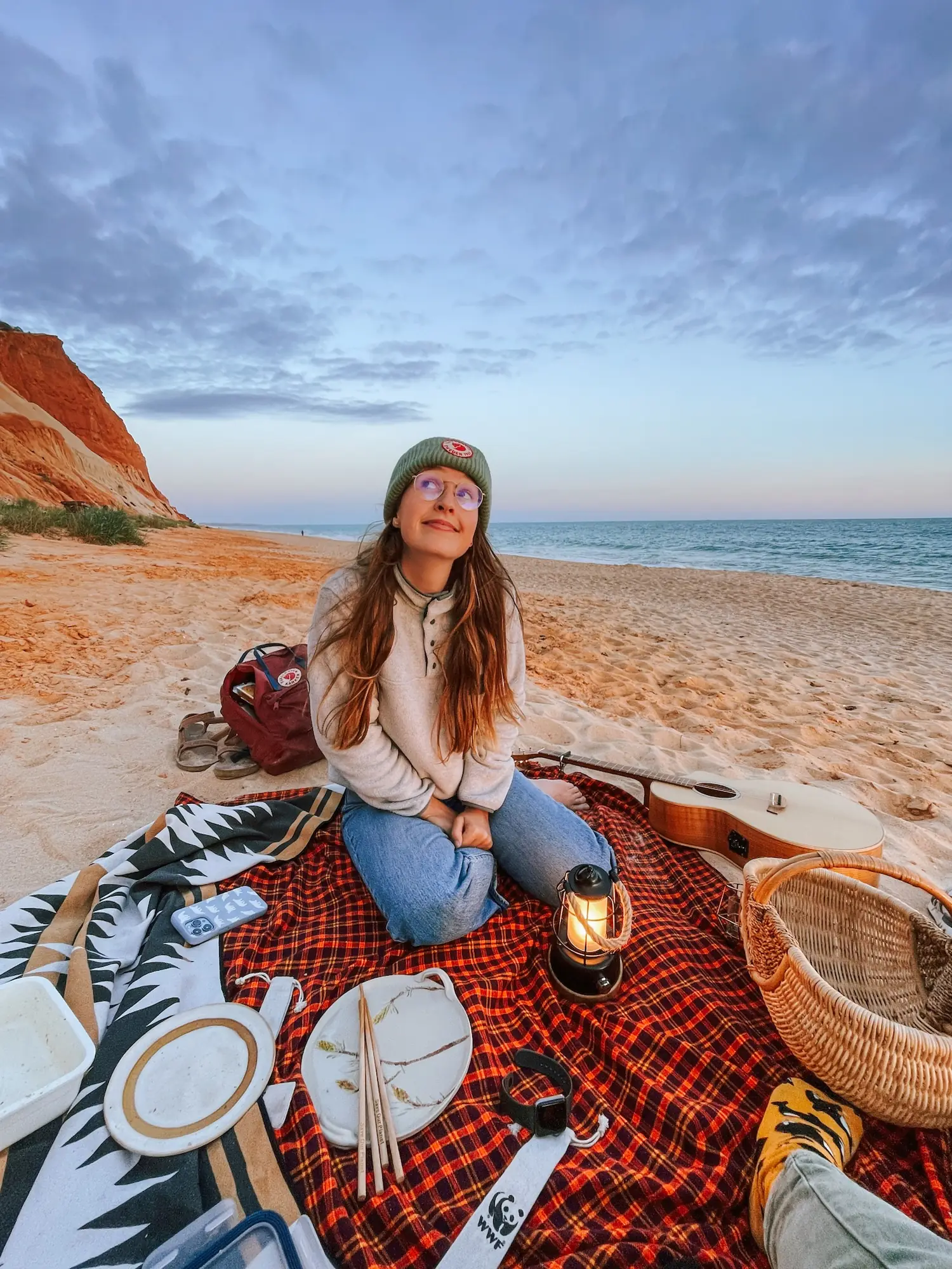 evelyne sitting on a beach with a picnic blanket