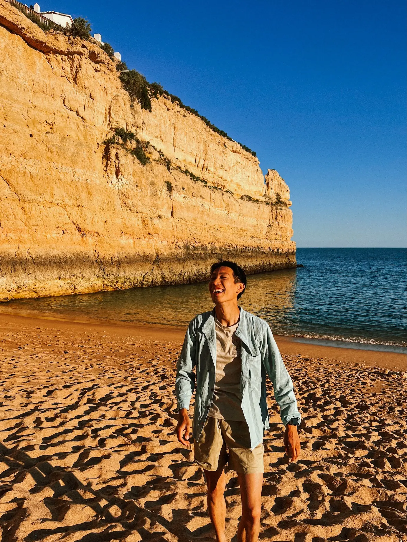 frank on a beach below golden cliffs