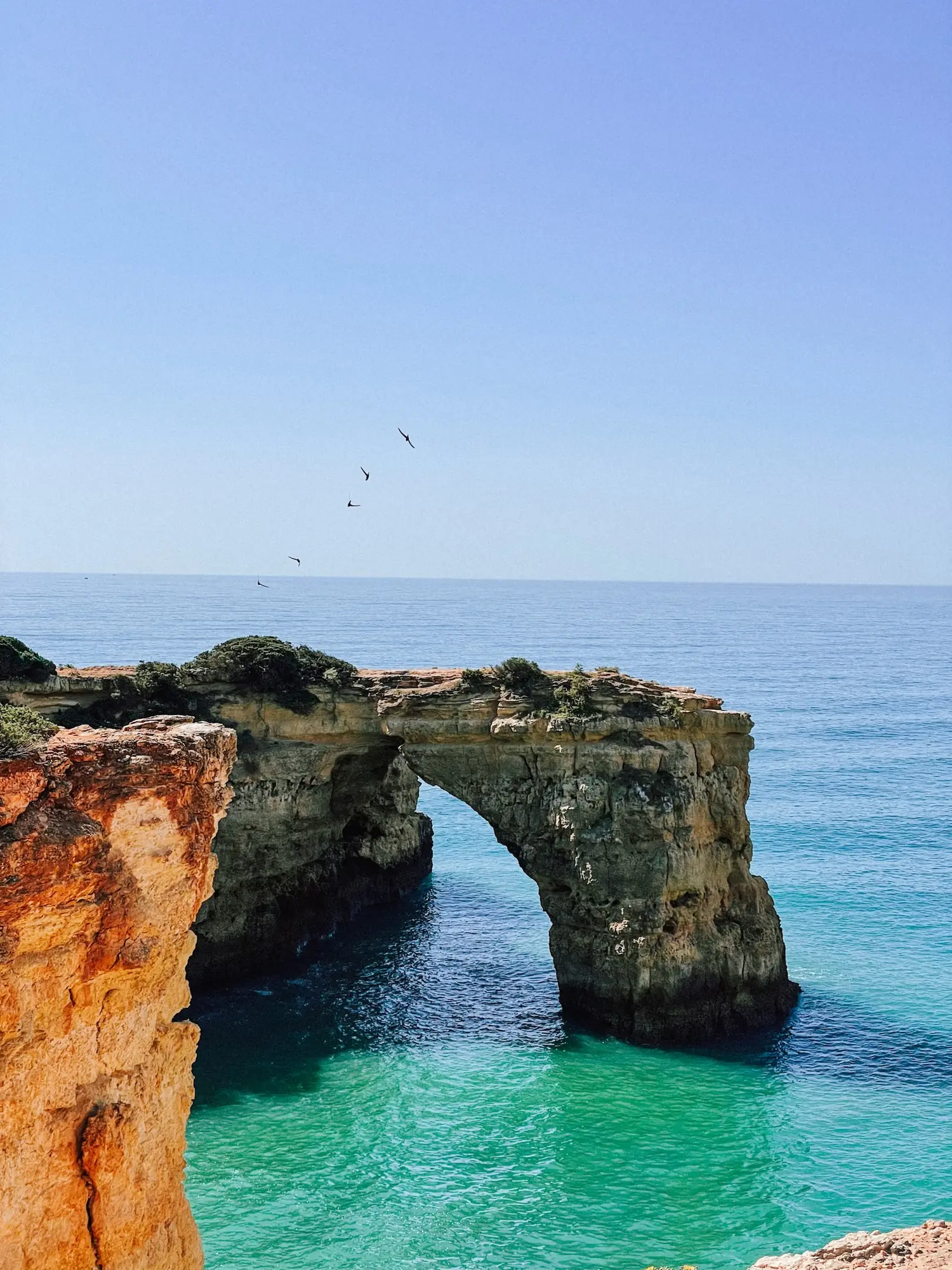 a natural rock arch over turquoise water