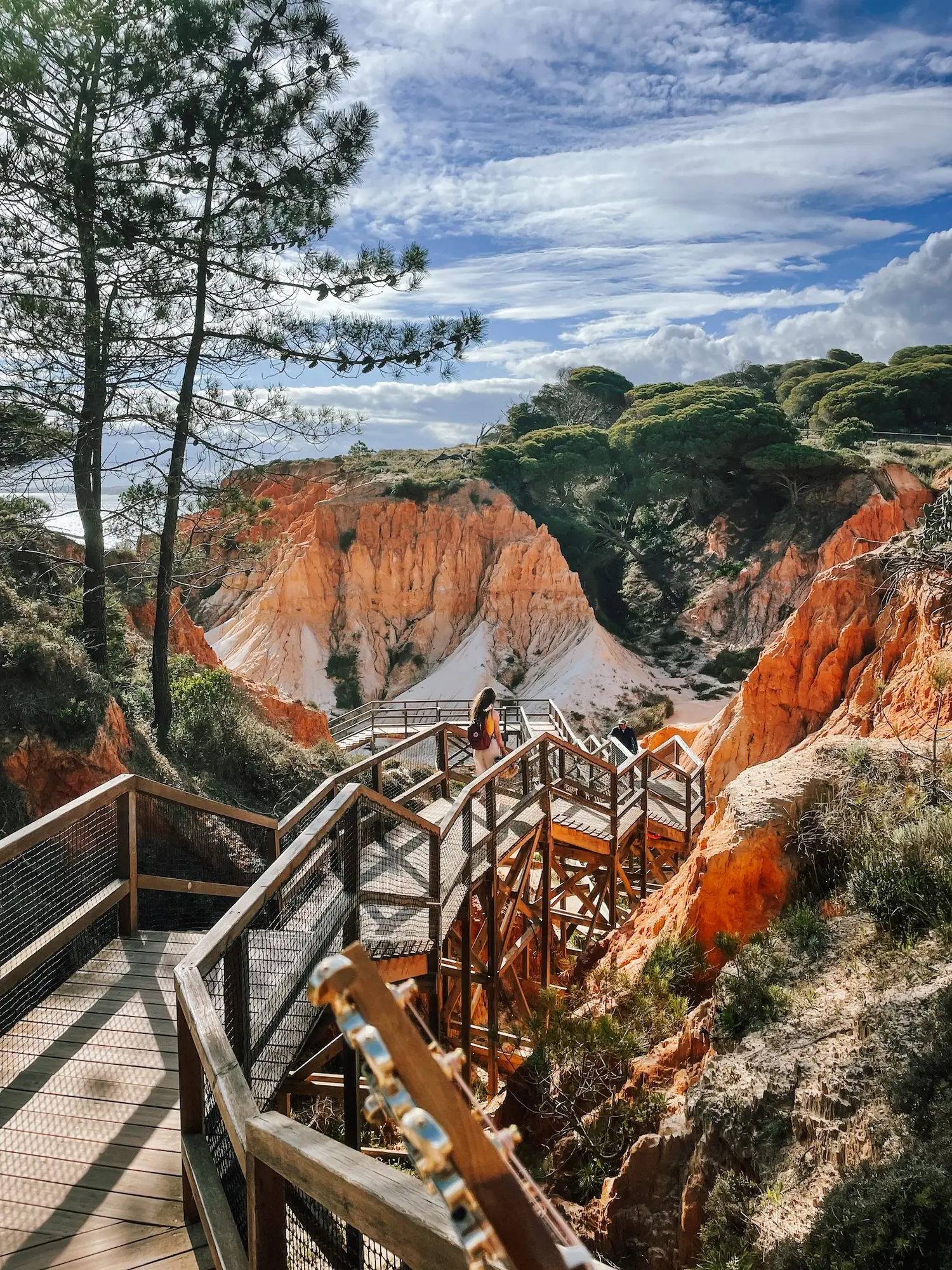 a boardwalk between red cliffs above the beach