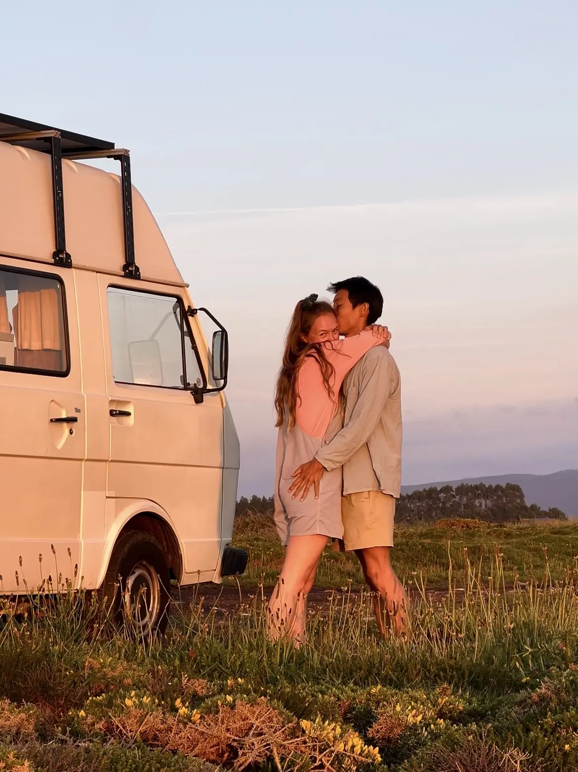 frank and evelyne kissing next to humbär at sunset