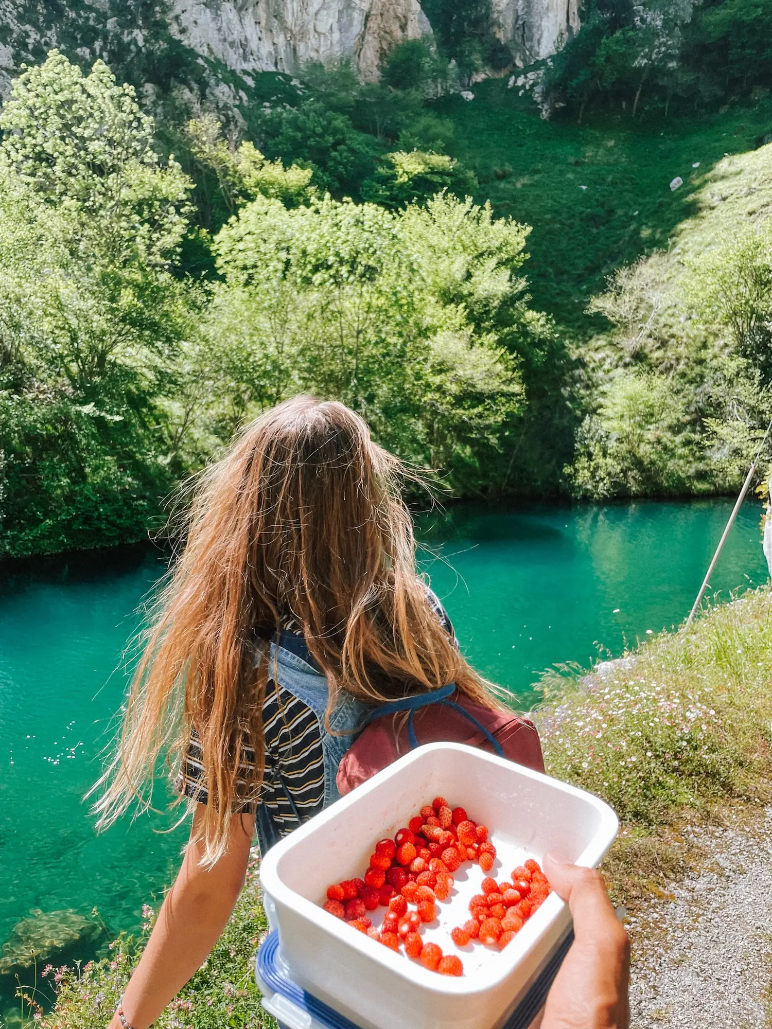 evelyne holding a box of wild strawberries by a turquoise river